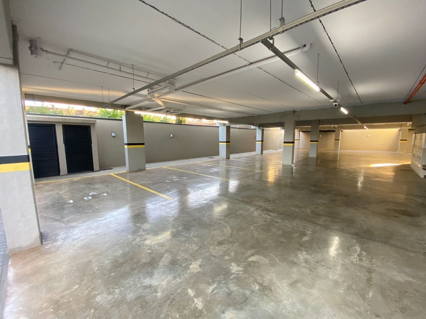 Garagem coberta ampla com iluminação e depósitos privativos