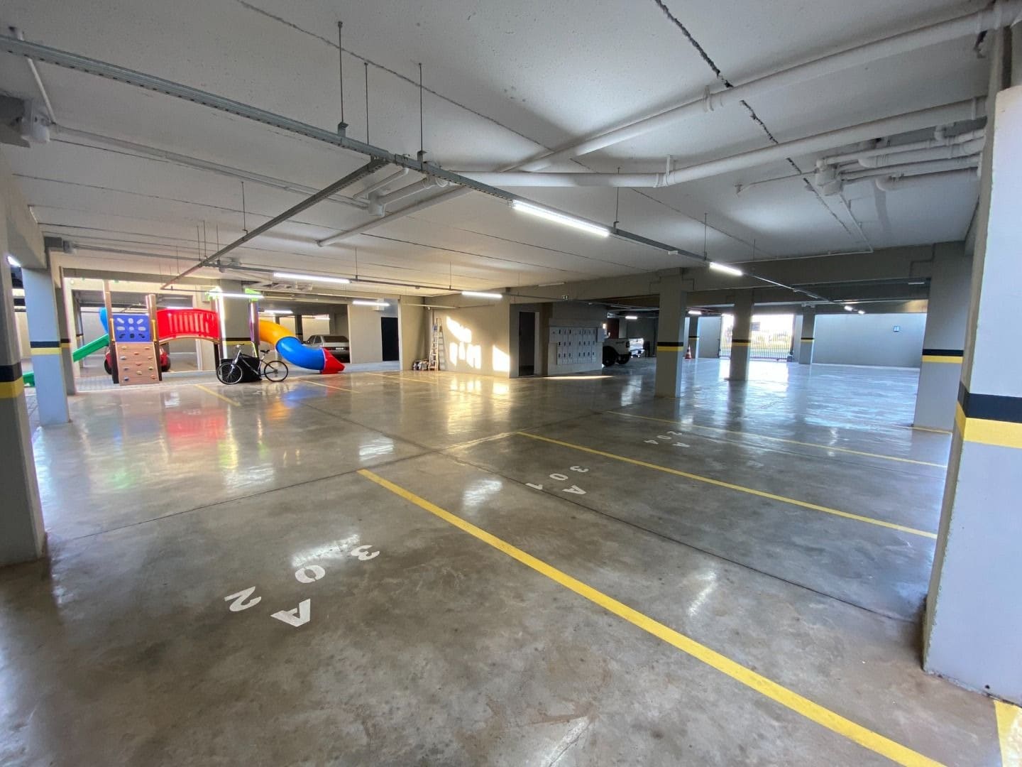 Garagem coberta com vagas demarcadas e acesso ao playground